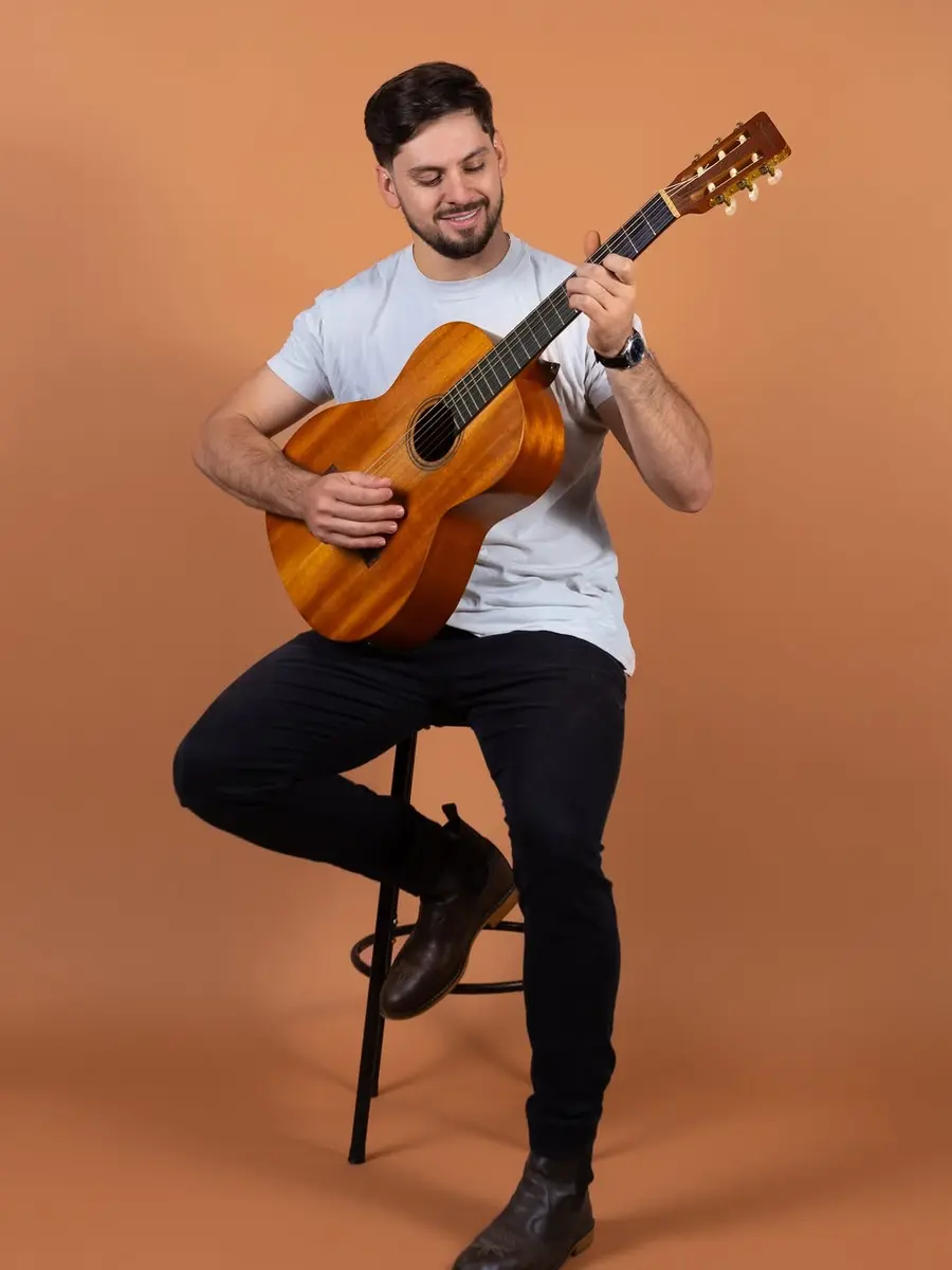 Paulo Andrade sentado com o violão no colo